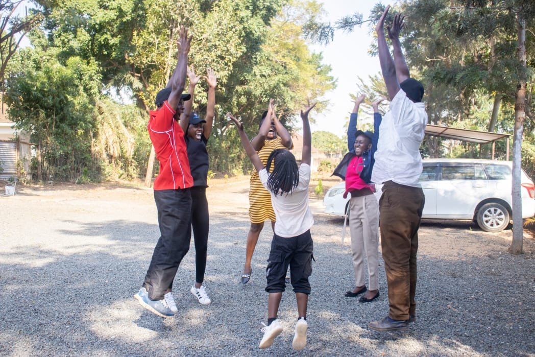 Children and therapists enjoying outdoor group exercise activities with arms raised